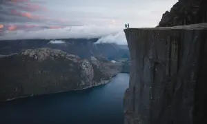 Två personer står på en klippavsats med hisnande utsikt över en fjord. Trots **höjdrädsla** vågar de sig nära kanten.