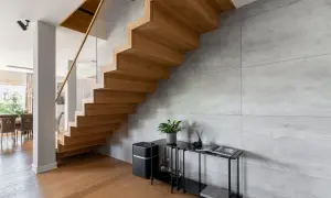 Nowoczesne schody dywanowe z drewna dębowego, szklana balustrada i beton architektoniczny tworzą elegancką przestrzeń.