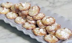 En hög med hembakade amaretti-kakor, pudrade med florsocker, redo att avnjutas. Ett enkelt amaretti recept.