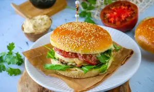 Un burger maison avec un pain aux graines de sésame, garni de légumes frais et de fromage fondant.