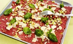 En läcker carpaccio med tunt skivat kött, pinjenötter, parmesan och basilika. Ett perfekt carpaccio recept för en förrätt.