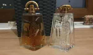 Dwie butelki Givenchy Pi: jedna pełna bursztynowego płynu, druga pusta, obie z ozdobnymi złotymi nakrętkami.