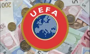 Logo UEFA na tle banknotów i monet euro. Symbolizuje finansowe fair play w europejskiej piłce nożnej.