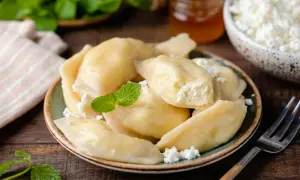 Pyszne pierogi z serem na słodko, udekorowane miętą i twarożkiem. Idealne na deser lub śniadanie.