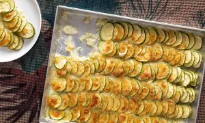 Fette di zucchine al forno con mozzarella filante, disposte in file ordinate in una teglia, pronte per essere gustate.