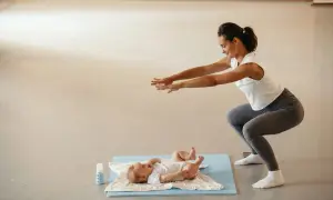 Madre haciendo sentadillas con su bebé cerca, un ejemplo de deporte postparto.