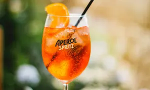 Ett glas med en orange Aperol Spritz, is och en apelsinskiva. Perfekt för en solig dag.