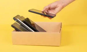 Ręka wkłada smartfon do kartonu z innymi telefonami. Chcesz wiedzieć, jak sprawdzić model telefonu?