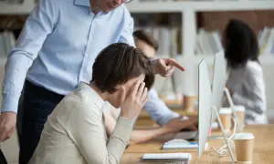 Uomo punta il dito contro collega in lacrime, un esempio di come provare il mobbing in ufficio.