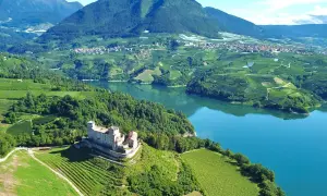 Castello di Thun domina il lago e i vigneti del Val di Non. Un paesaggio incantevole da esplorare, tra storia e natura.