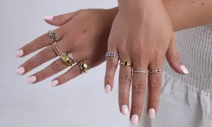 Manos con uñas rosa pálido y anillos de plata y oro. Un anillo dorado tiene un sello, otro un diamante. ¿Qué significa 925 en oro?
