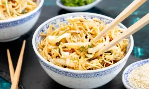 Ein Schüsselchen "friss dich dumm Salat" mit Nudeln, Gemüse und Mandeln, bereit zum Genießen mit Stäbchen.