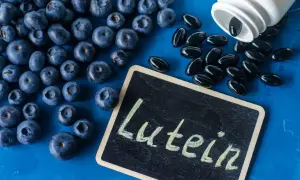 Jagody i kapsułki suplementu diety z napisem "Luteina" na tabliczce. Luteina na oczy wspiera zdrowie wzroku.