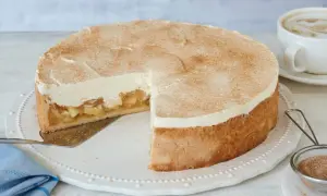 Saftige Apfel Schmand Torte mit Zimt bestäubt, bereit zum Servieren neben einer Tasse Kaffee.
