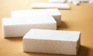 Białe bloki styropianu na brązowym tle. Czy styropian pije wodę? Ten materiał jest lekki i porowaty, ale nie wchłania wilgoci.