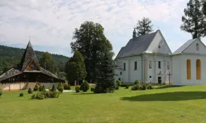 Ustrzyki Dolne atrakcje: drewniana cerkiew i biały kościół na tle zielonych wzgórz.