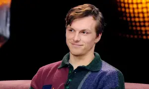 Uśmiechnięty Tomasz Włosok w kolorowym swetrze, jakby opowiadał o swoich najnowszych filmach.