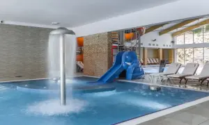 Relaks w hotelu w Szklarskiej Porębie z aquaparkiem: basen, zjeżdżalnia w kształcie słonia, wodospad i leżaki.