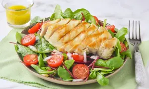 Deliciosa ensalada de pollo a la parrilla con tomates cherry, hojas verdes y aderezo.