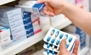 Ręka wybiera lek z półki, w dłoni trzyma opakowania z kapsułkami. Szuka lercan zamienniki.