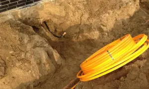 Baustelle: gelbe Rohre liegen bereit für die Gasleitung verlegen im Erdreich. Ein Graben ist ausgehoben.