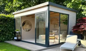 Modernes Gartenhaus mit Glasfront, das zum Streichen einlädt. Gemütliche Inneneinrichtung mit Rattankorb-Lampe und Liegestuhl draußen.
