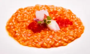 Risotto al porto cremoso con gamberi, pomodorini e un tocco di verde.