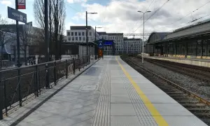 Peron 6 na dworcu Wrocław Główny, z którego odjeżdża pociąg. Nowoczesny peron z żółtym pasem bezpieczeństwa i budynkami w tle.