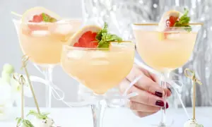Tre eleganta glas med rosa drinkar, garnerade med grapefrukt och mynta. Perfekt drink till nyår!