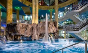 Interior de un balneario en la Comunidad Valenciana con piscina, cascadas, rocas artificiales y escaleras.