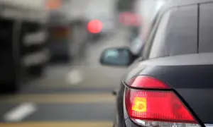 Gros plan sur les feux arrière d'une voiture dans un trafic dense. Le feu de freinage est allumé, signalant un arrêt imminent.