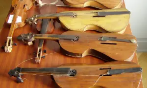 Na stole leży kilka instrumentów smyczkowych. Jeden z nich to pudło skrzypiec, które wygląda na bardzo stare.