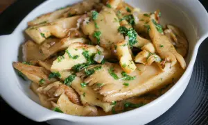 Délicieuse pleurote recette, des champignons sautés aux herbes fraîches dans un plat blanc.