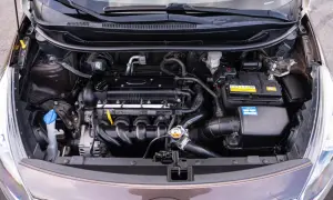 Silnik Kia Rio 3 z widocznym akumulatorem, przewodami i innymi elementami układu napędowego.