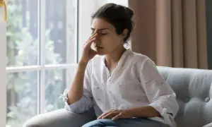 Mujer sentada en un sofá, con la mano en la frente, sintiendo la decepción de cuando esperas algo de alguien y no llega.