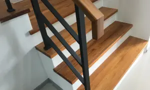 Moderne Treppen aus Holz mit schwarzem Geländer in einem Einfamilienhaus.