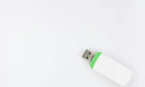 Biały pendrive z zieloną opaską, gotowy do podłączenia. Ten woe usb pomieści Twoje dane.