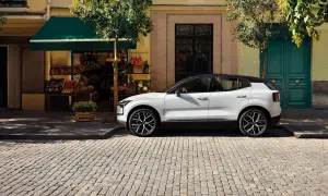Vit Volvo parkerad på kullerstensgata framför en färggrann fasad. Upptäck olika volvo utrustningsnivåer för din nästa bil.