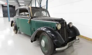 En grön och svart DKW med en spånkorgsdetalj på taket, står i ett garage.