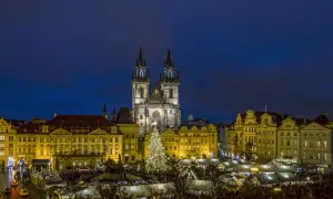 Prag im Winter: Der beleuchtete Weihnachtsbaum auf dem Altstädter Ring, umgeben von Ständen und der Teynkirche, erstrahlt in der Dämmerung.