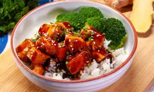Aksamitny łosoś w sosie teriyaki, podany z ryżem i brokułami, posypany sezamem i szczypiorkiem. Pyszne danie gotowe do spożycia.