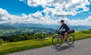Frau auf Radtour durch Deutschland, genießt die Aussicht auf grüne Hügel und Berge. Perfekt für eine 3 Tage Radtour Deutschland.