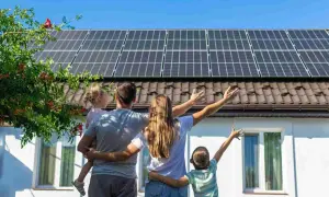 Familia celebra el **revamping fotovoltaico** de su hogar, con paneles solares en el tejado y un futuro brillante.