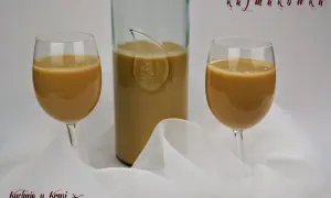 Kajmakówka, czyli likier krówkowy z masy kajmakowej, w kieliszkach i butelce, na tle białej tkaniny.