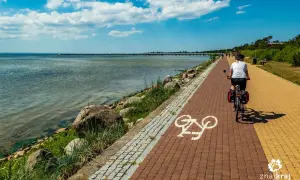 Kobieta na rowerze przemierza malowniczą trasę rowerową Władysławowo Hel. Widok na morze i molo.