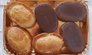 Sei fruttoni leccesi, tre ricoperti di cioccolato fondente e tre dorati, disposti su un vassoio dorato.