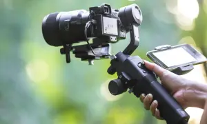 Ręka trzymająca stabilizator do kamery, czyli co to gimbal. Umożliwia płynne nagrywanie filmów.