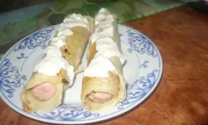 Dwa parówki w cieście naleśnikowym, polane sosem. Pyszna przekąska na szybko.