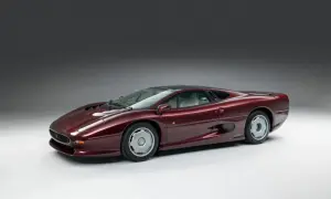 Bordowy Jaguar XJ220, ikona lat 90., prezentuje swoje aerodynamiczne linie na tle szarego studia.