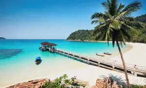 Traumhaftes Malaysia Wetter im Juli: Türkisblaues Meer, weiße Sandstrände, Palmen und eine Anlegestelle mit Booten. Perfekt für einen Urlaub!